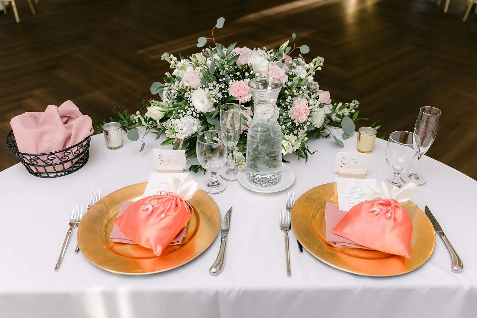 Gold charger place setting with a blush napkin and floral centerpiece