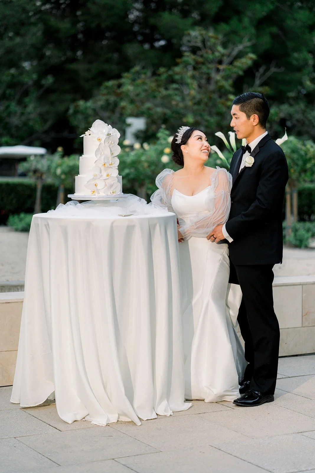 Steven and Jacinda stand beside their orchid topped cake