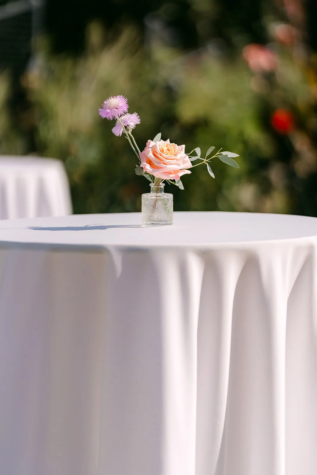 A single bloom in a bud vase on a cocktail table