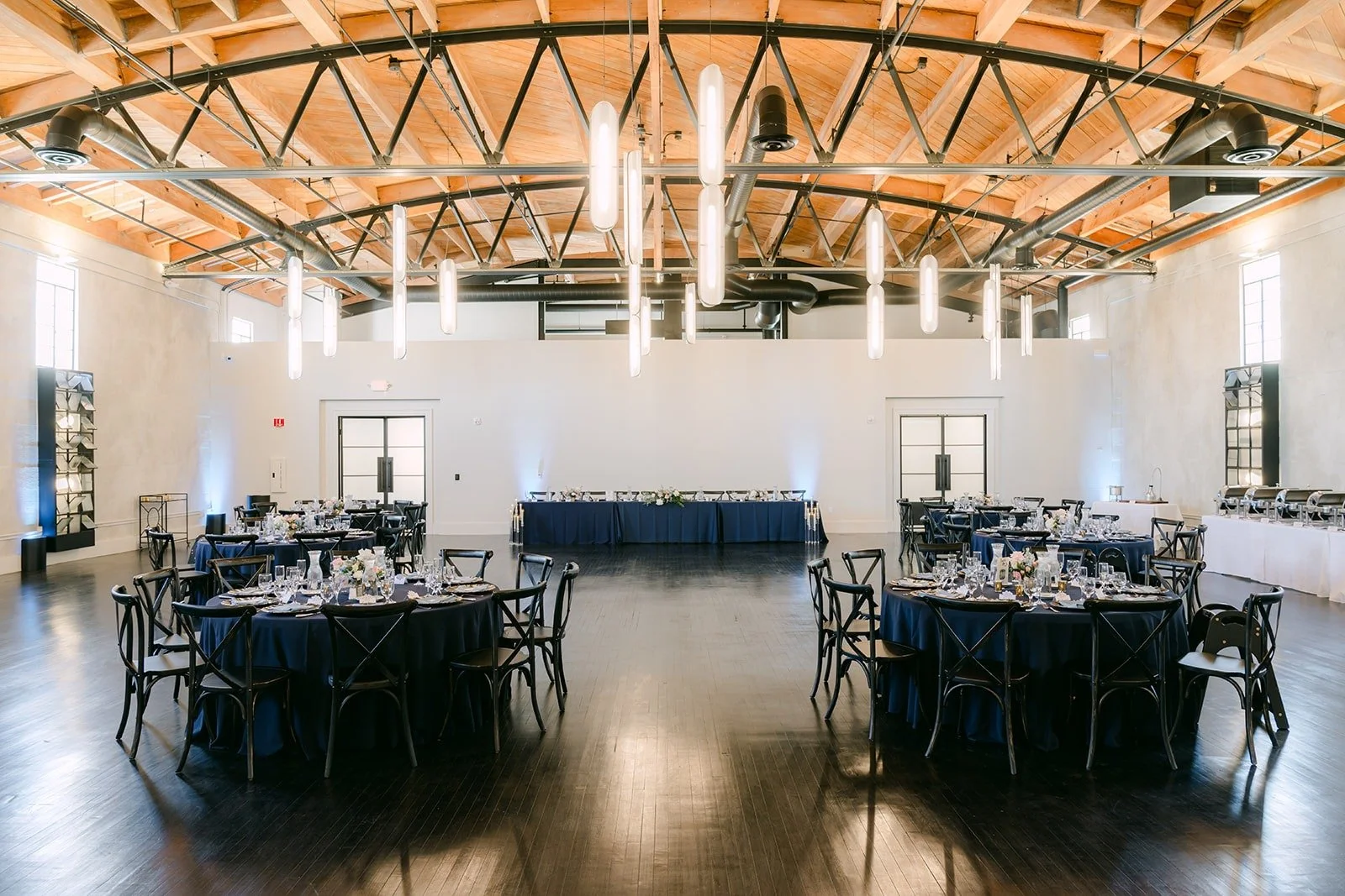 The reception room at The Headquarters with navy tables under the exposed wood beams