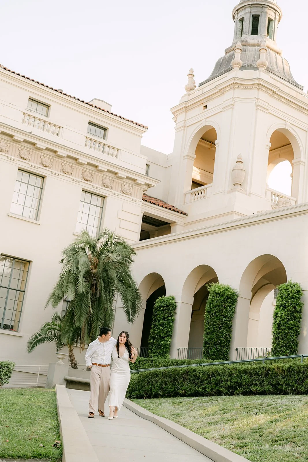 Emily and James walk across the courtyard toward the Pasadena City Hall tower, photographed by One and Only Production.