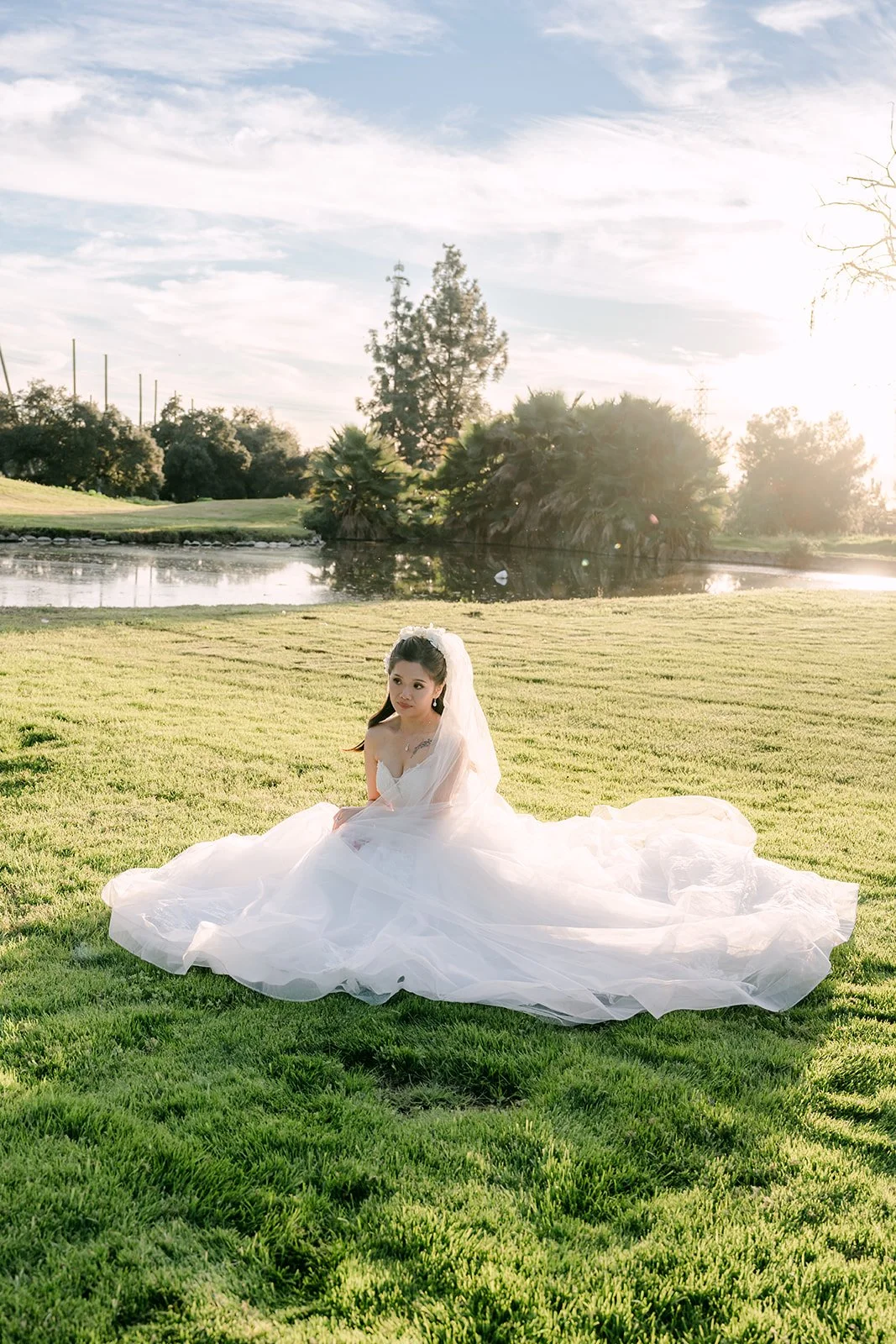 Kate sitting on the grass with her gown spread around her.