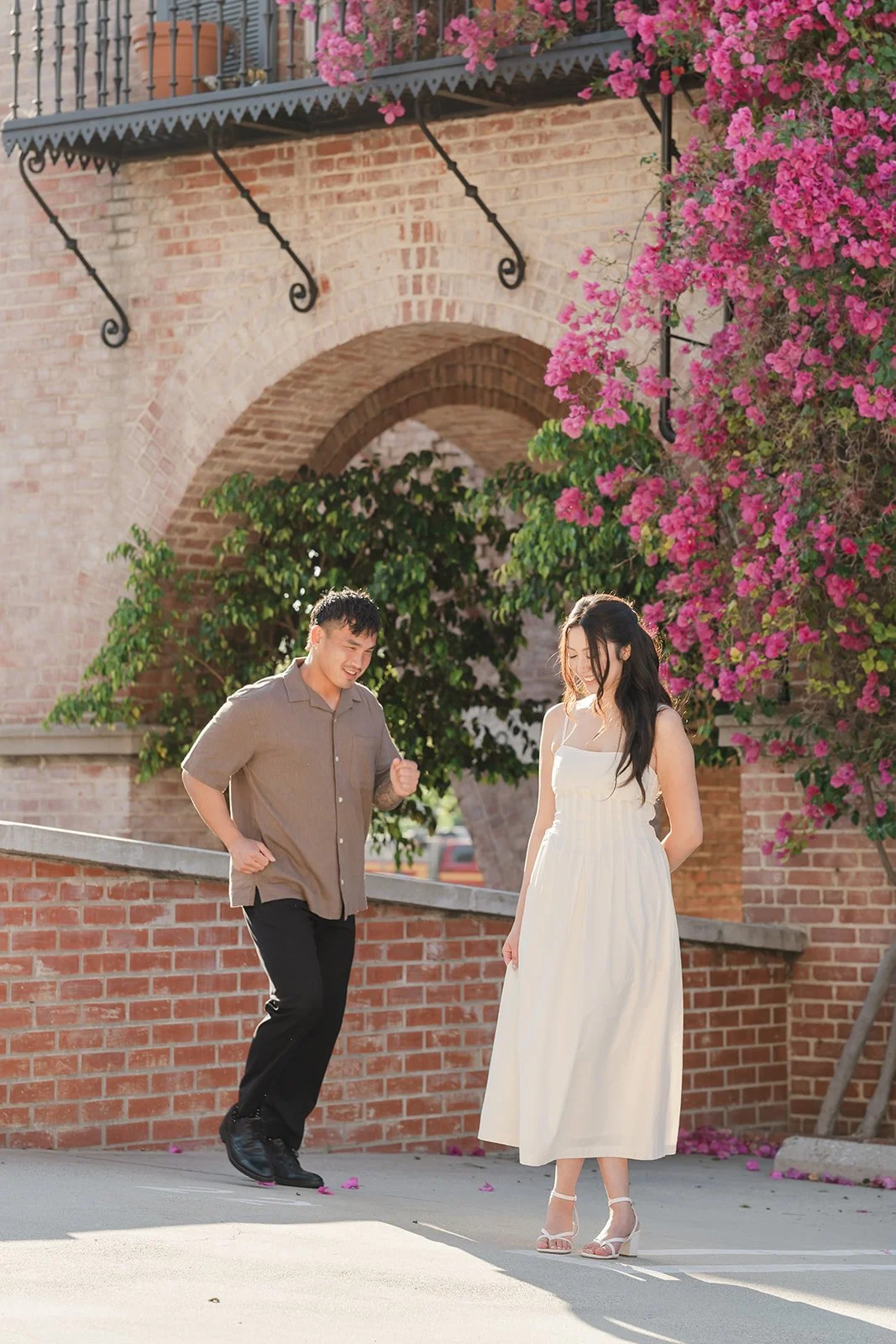 Andrew and Victoria reach for each other below the bougainvillea at Malaga Cove Plaza.