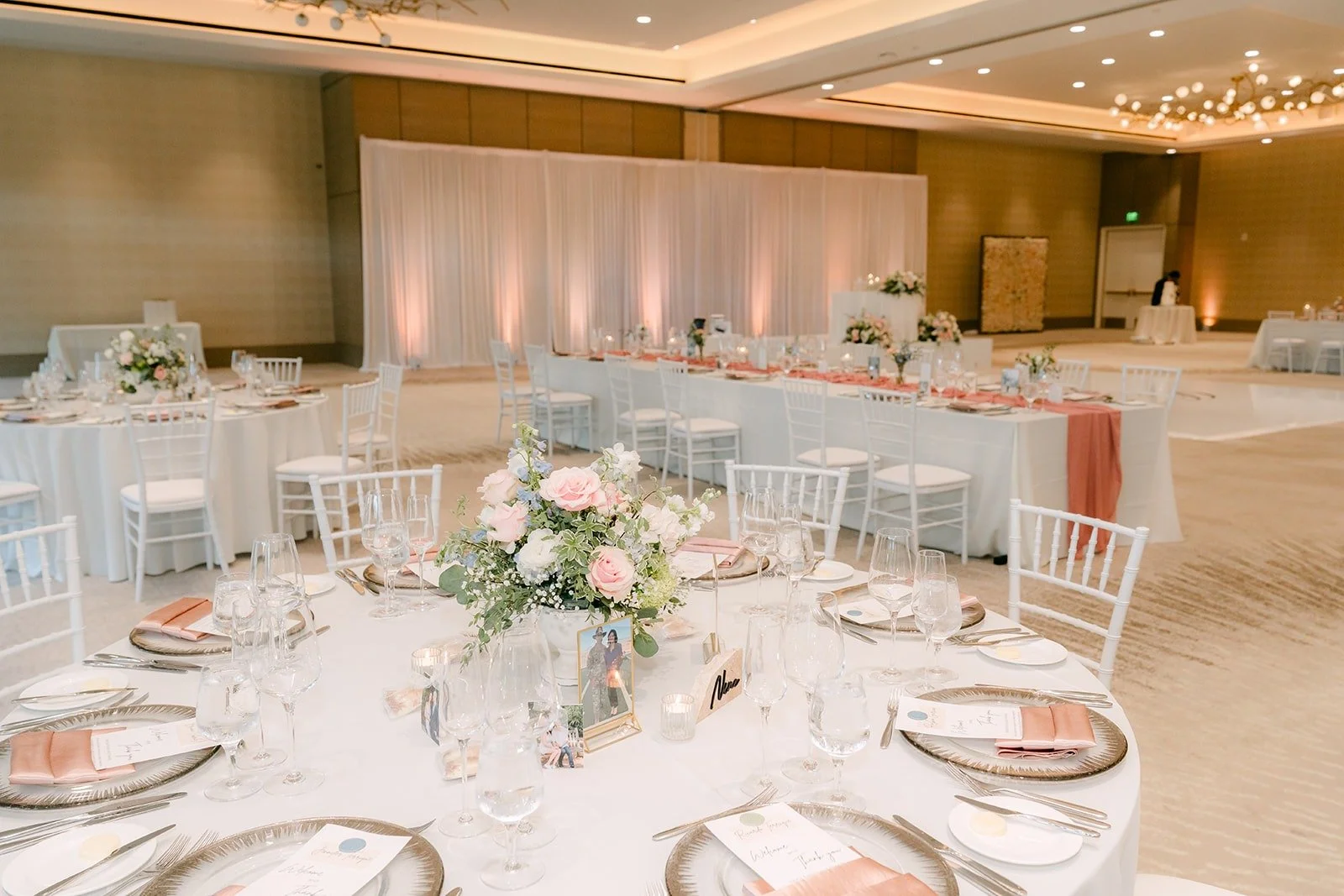 Long and round tables with blush runners and white florals in the ballroom