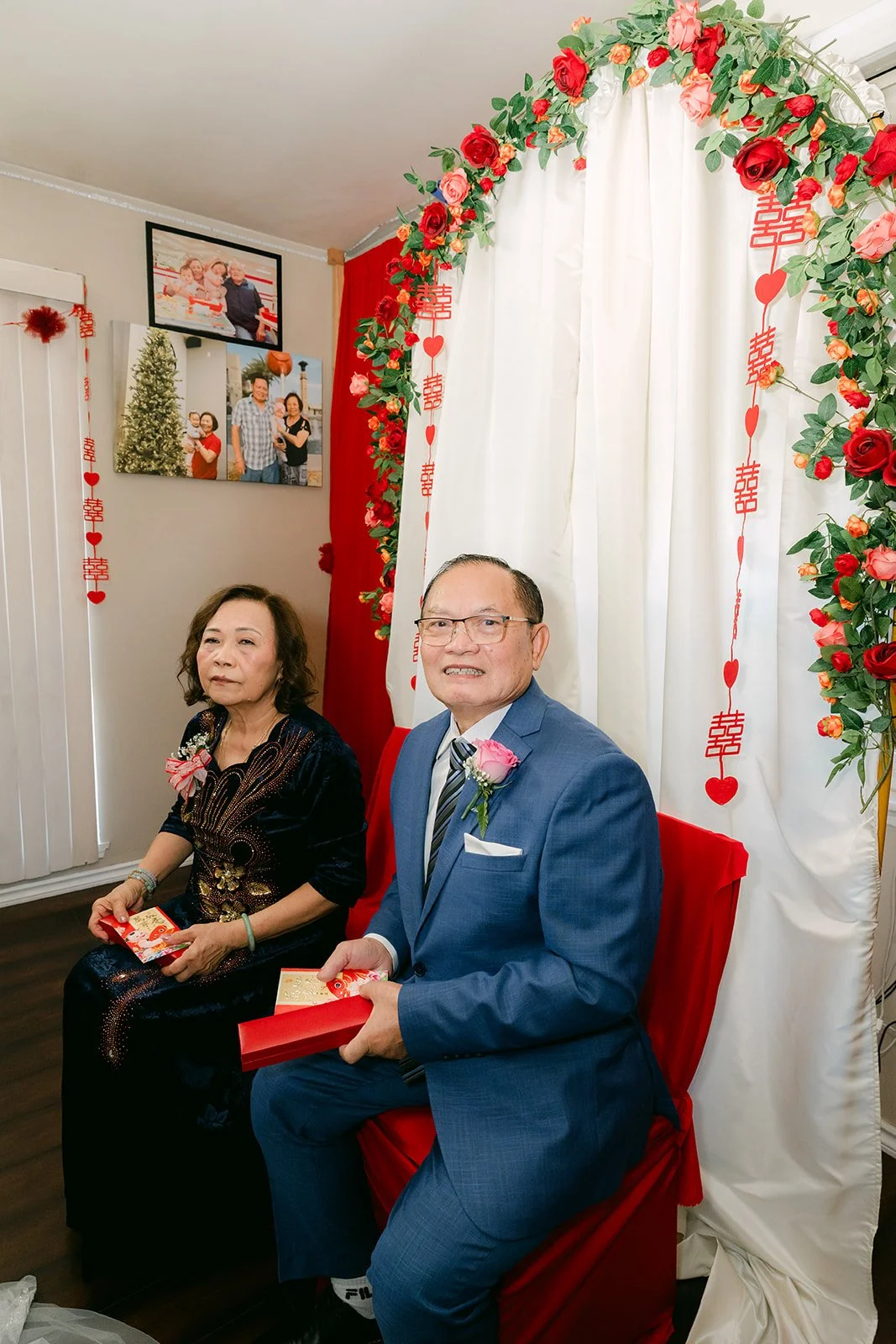Vanessa's parents smiling on the red chairs.