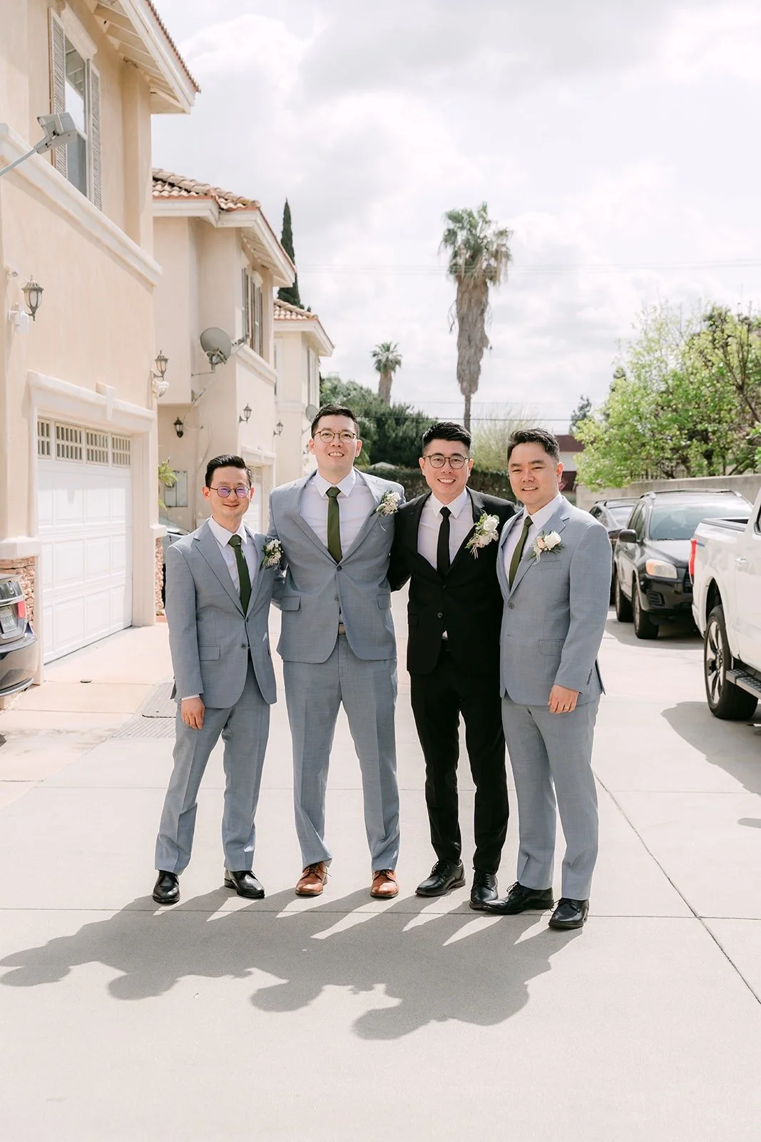 Eric and his groomsmen in gray suits lined up on the street outside the house