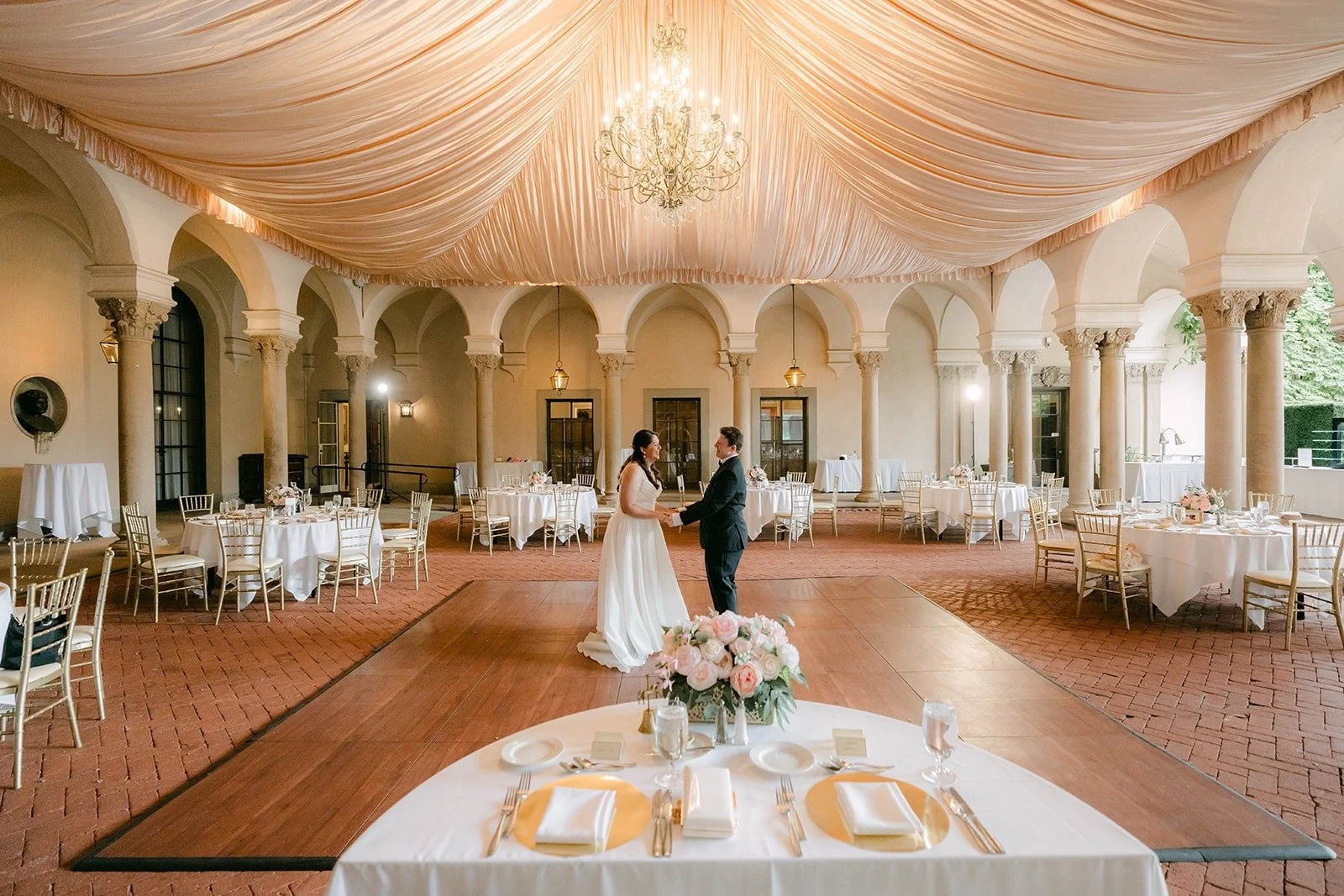 A wide view of their private first dance under the draped ceiling