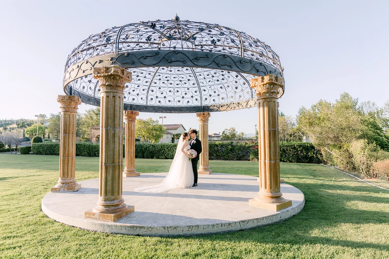 Bride and groom under the iron gazebo on the lawn at Vellano Estate