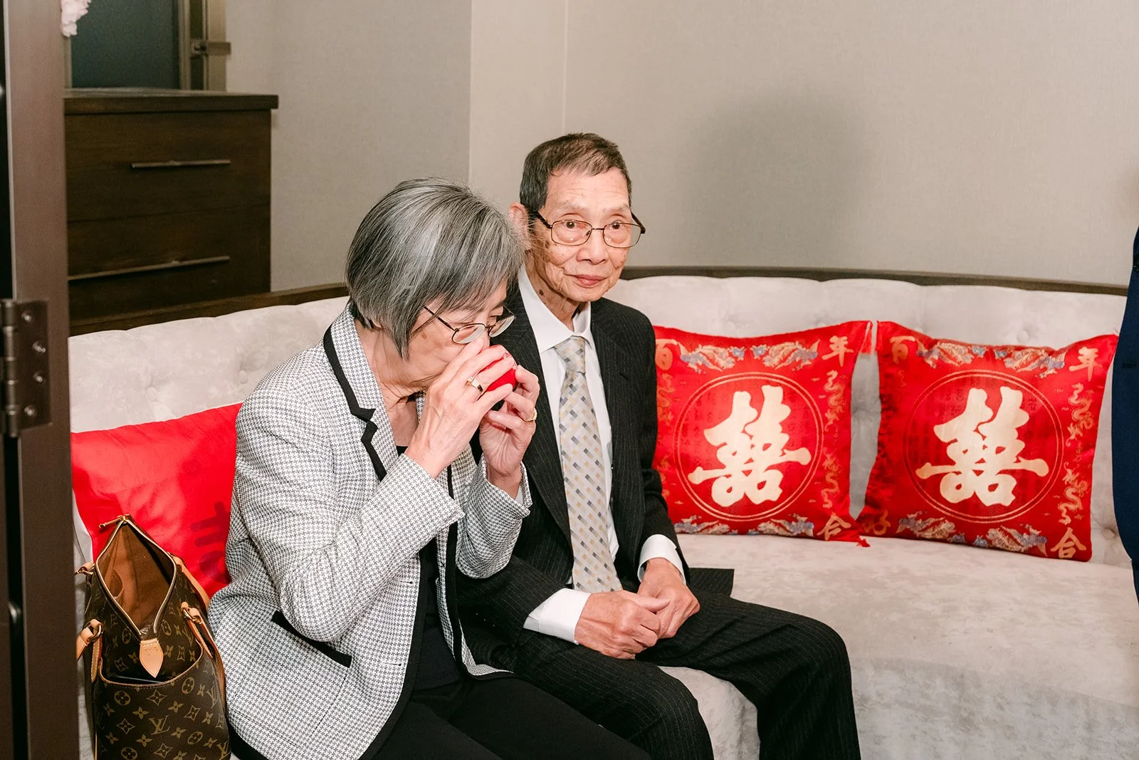 Relatives sipping tea on the couch.
