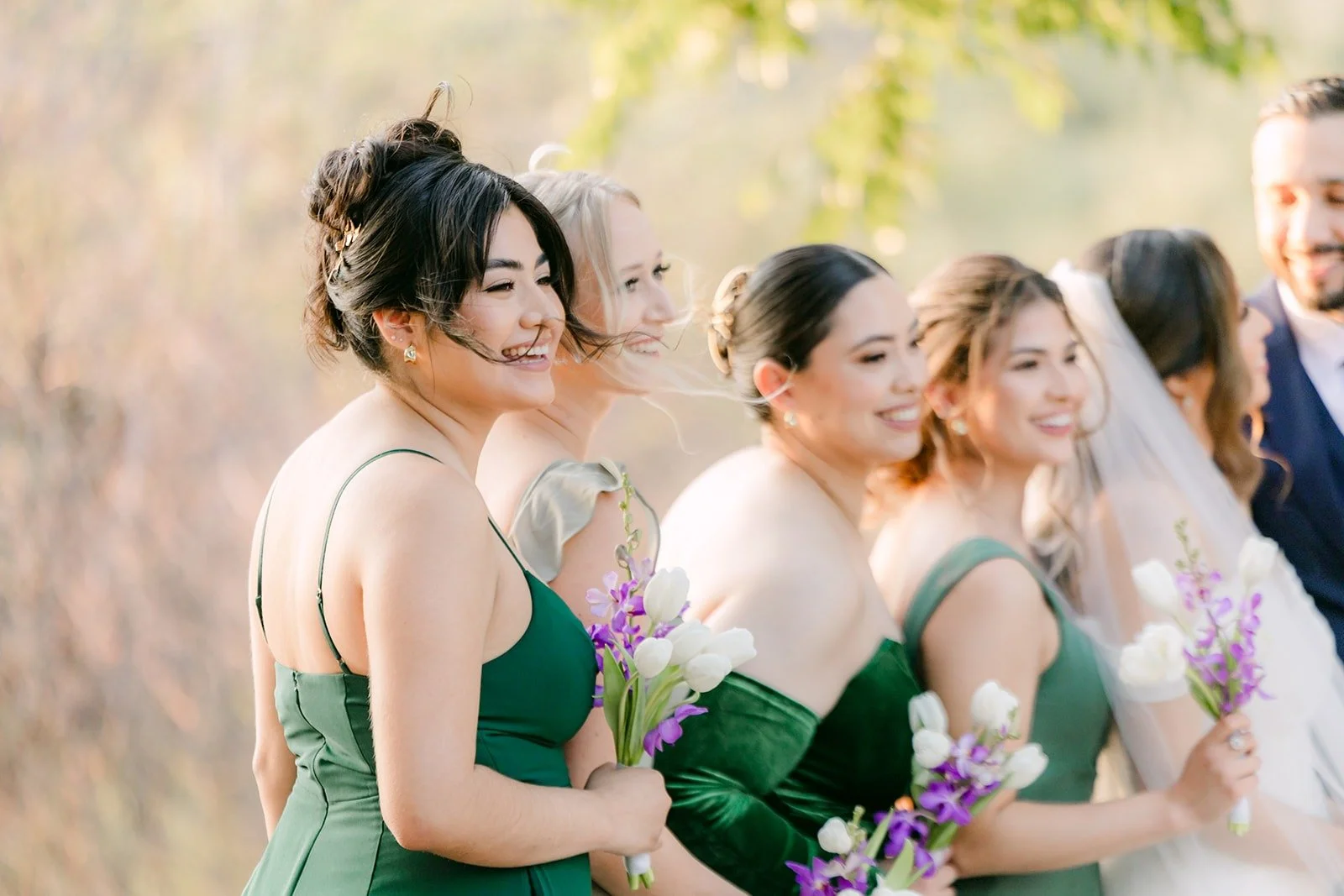 Bridesmaids laughing together with their purple and white bouquets