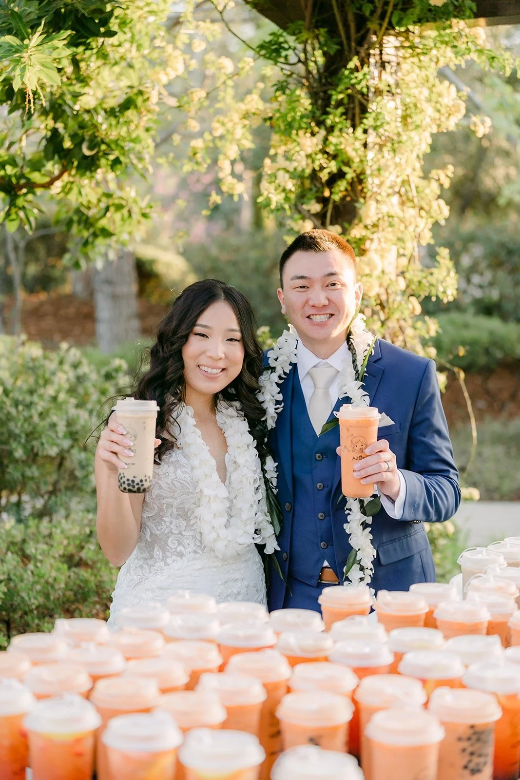 Kelli and Alex holding up boba drinks behind the full boba table