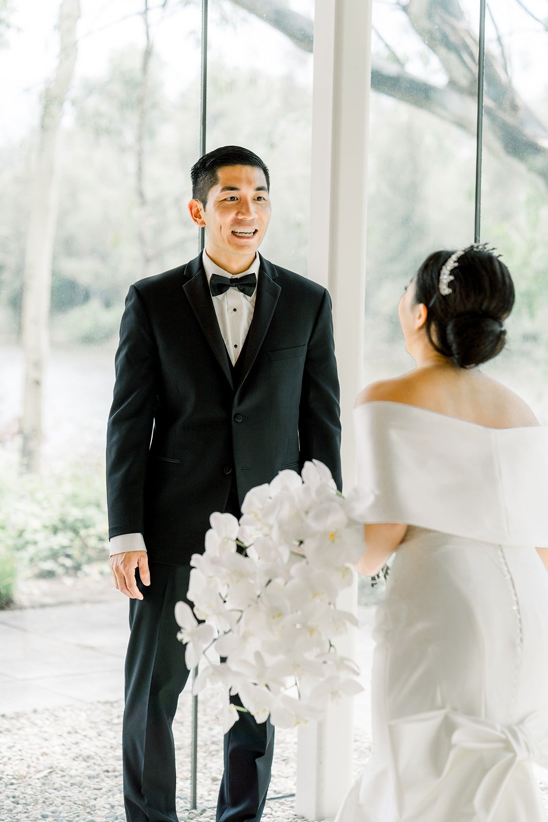 Steven and Jacinda face each other as she holds her orchid bouquet