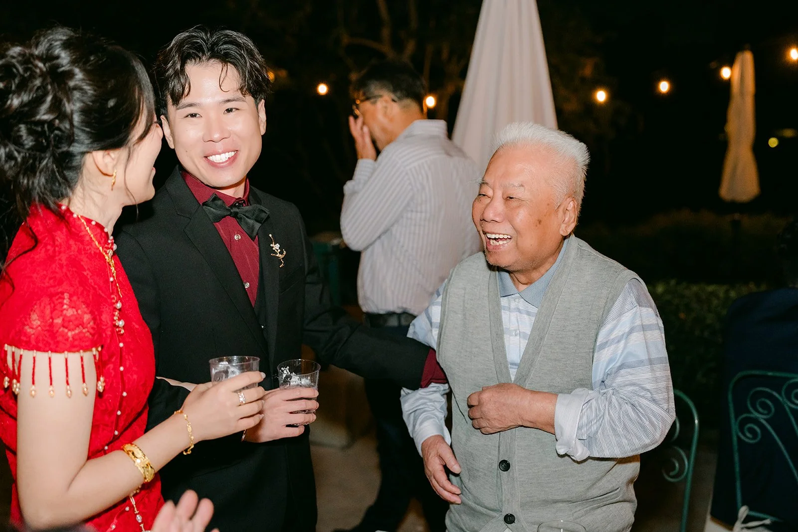 Elaine and Wen laughing with a relative during table toasts.