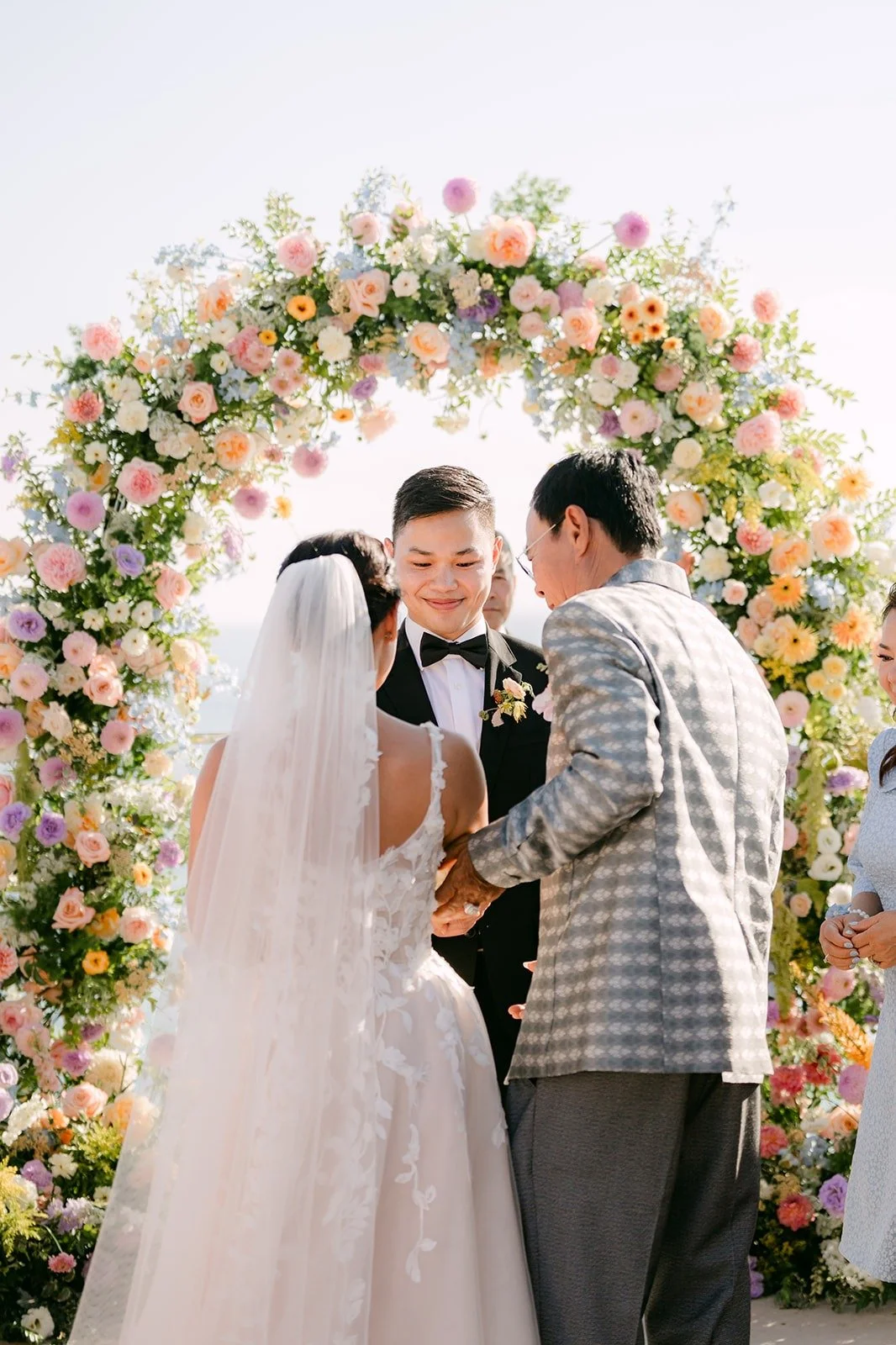 Kylie and Mario meeting under the arch as the officiant looks on