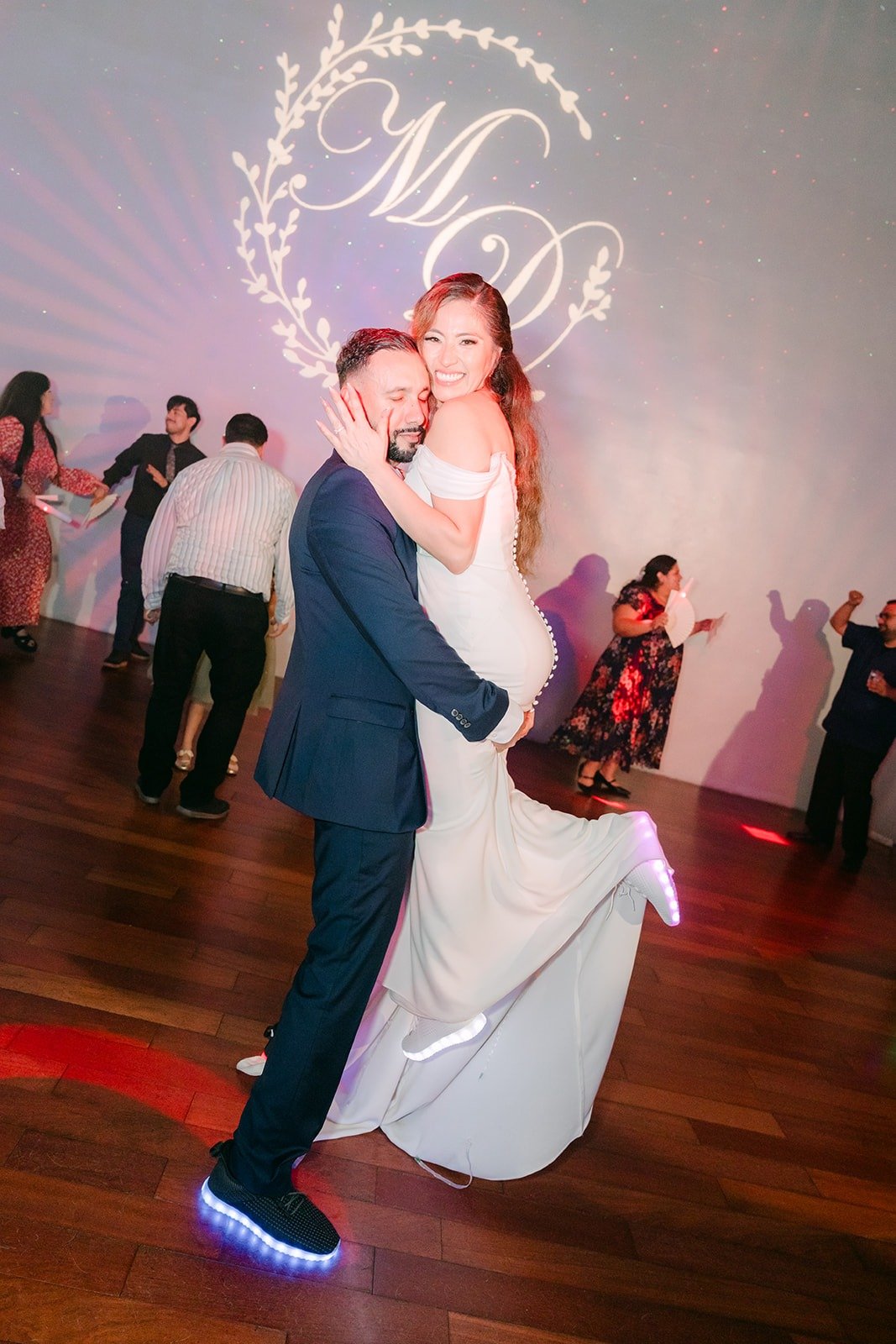 Danny lifting Mariana in front of their monogram