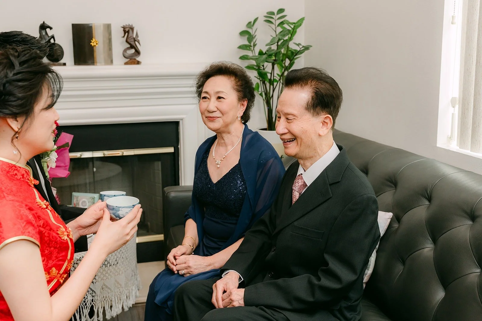 Eunice serves tea to family members seated on the sofa