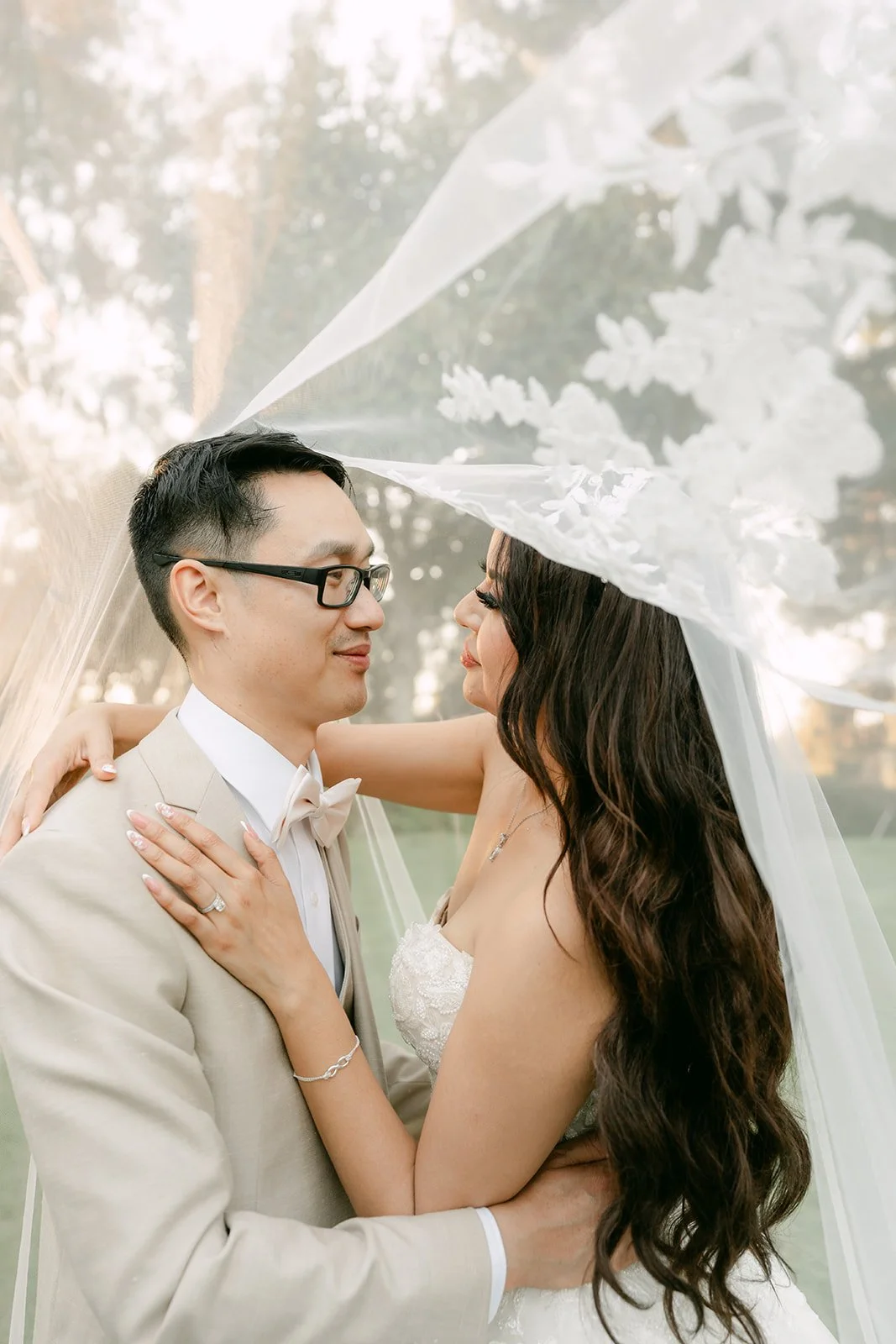 Kevin holding Sandra close under her lace veil, photographed by One and Only Production.