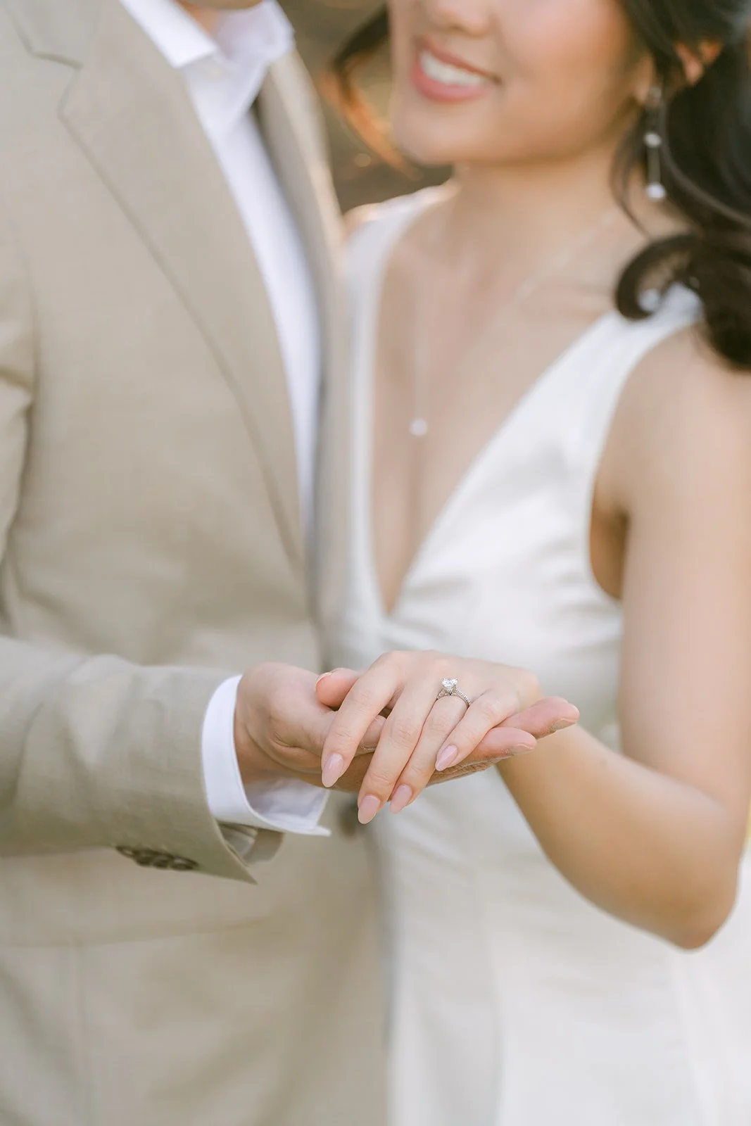 Detail of Kim holding Vincent's hand against his tan suit.