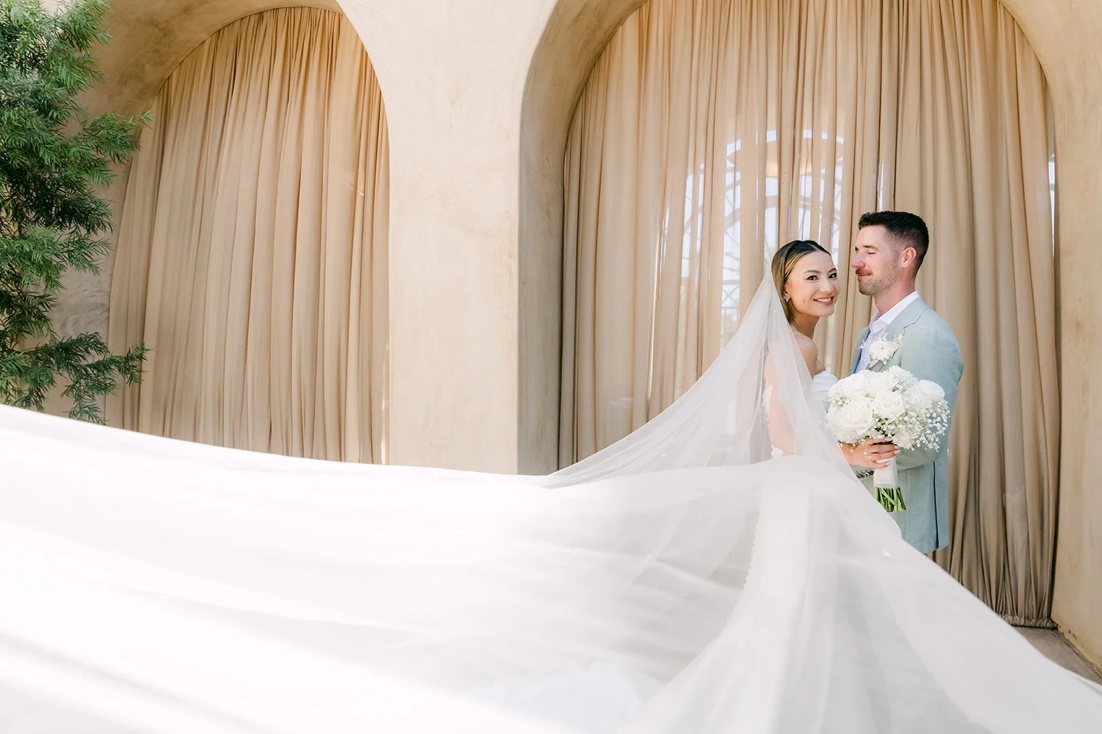 Kieu's long veil flowing in the breeze as she leans into Anthony
