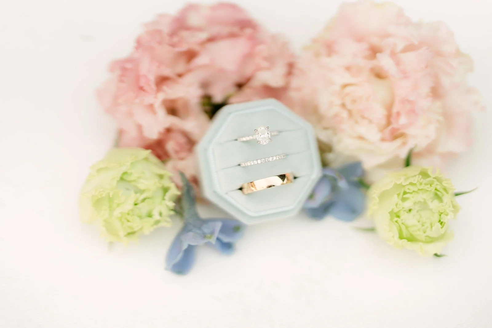 Blue velvet ring box framed by blush roses and green blooms, photographed by One and Only Production