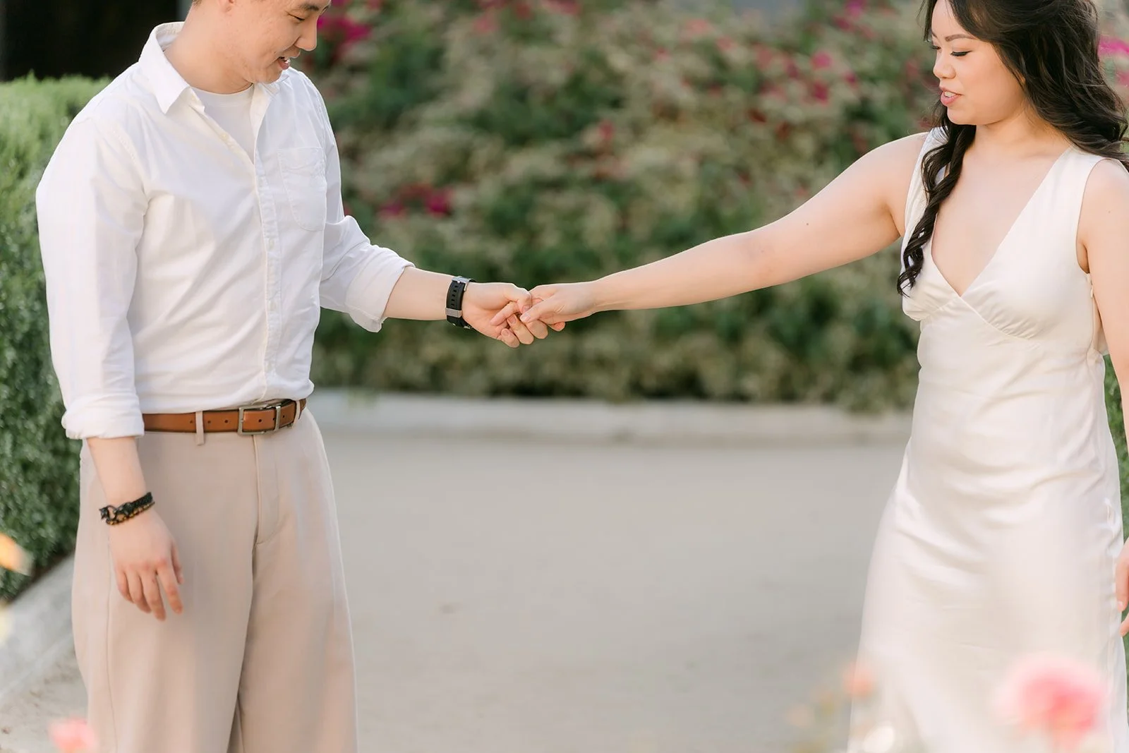 James leads Emily by the hand along the rose garden path.