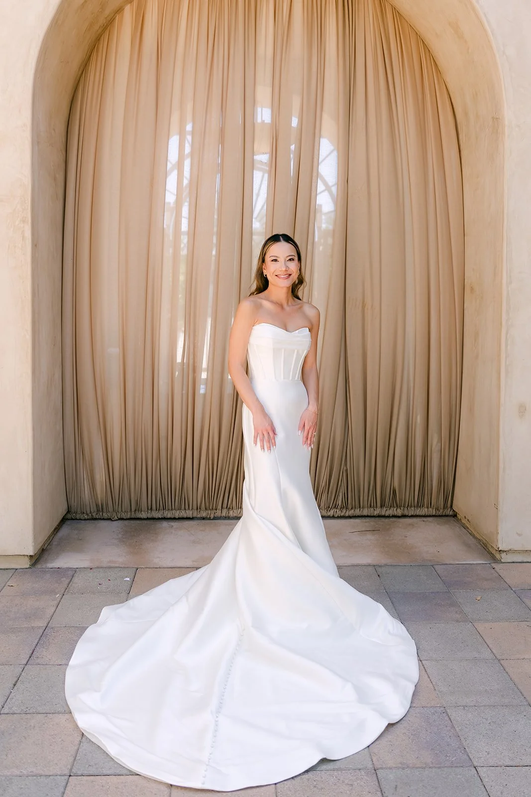 Mermaid gown and train spread out beneath a curtained arch at Serra Plaza