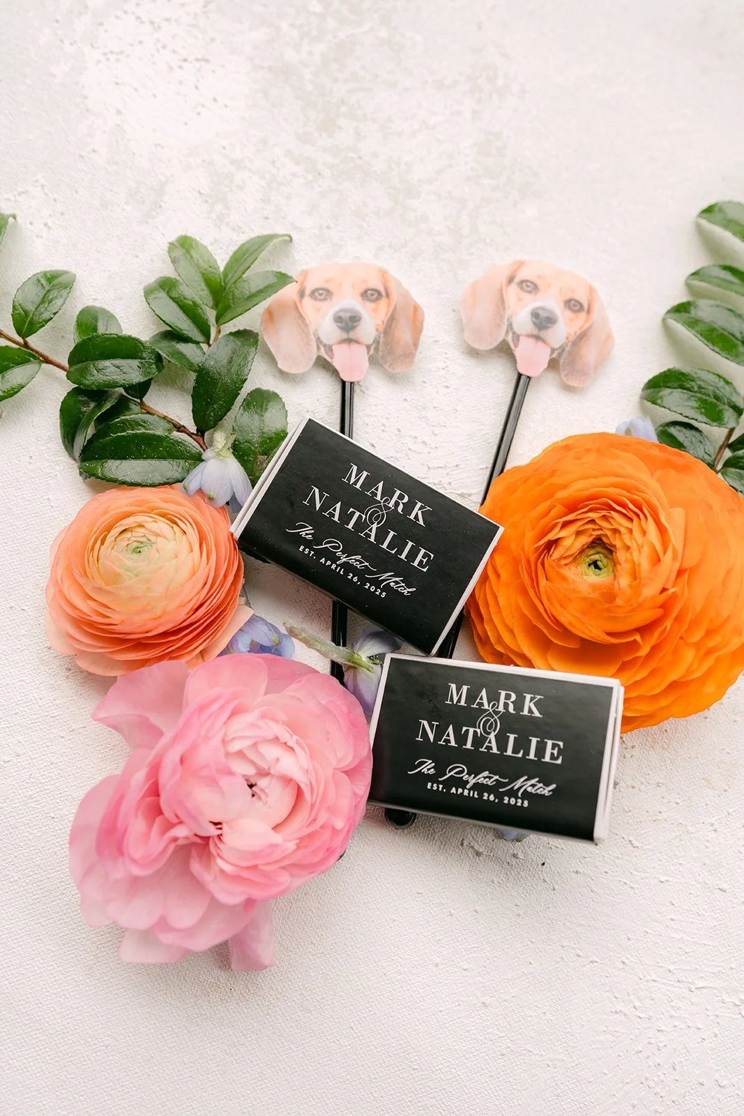 Black matchbook favors printed with Mark and Natalie's names, set between pink and orange flowers