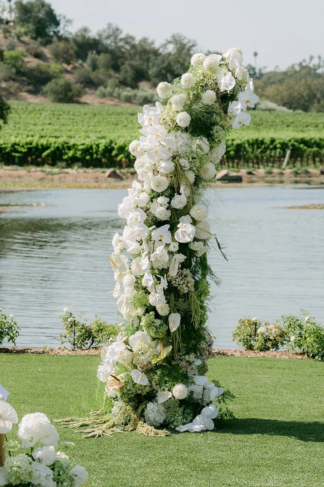 Floral column of white roses and orchids beside the pond and vineyard