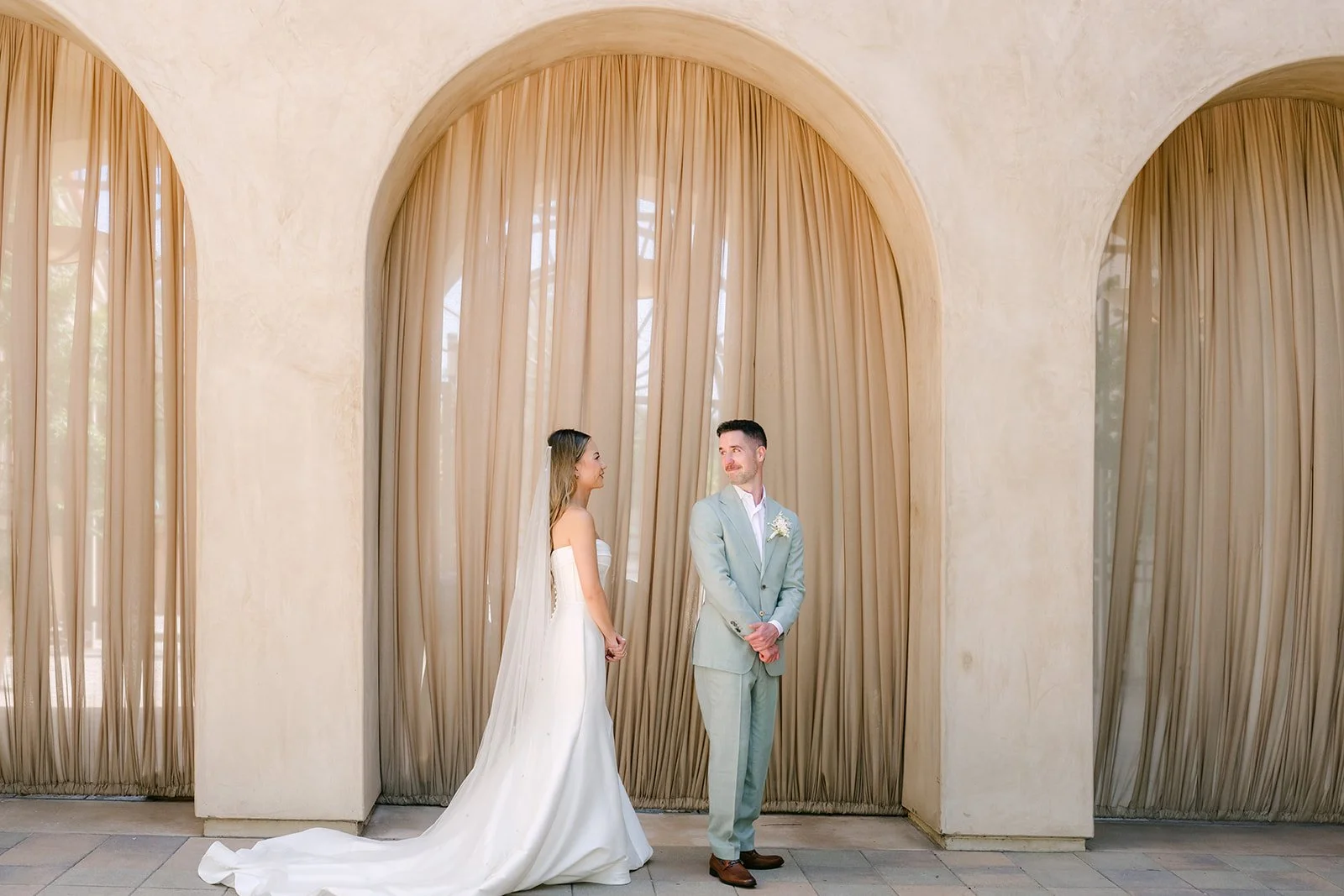 Kieu and Anthony facing each other between the draped arches