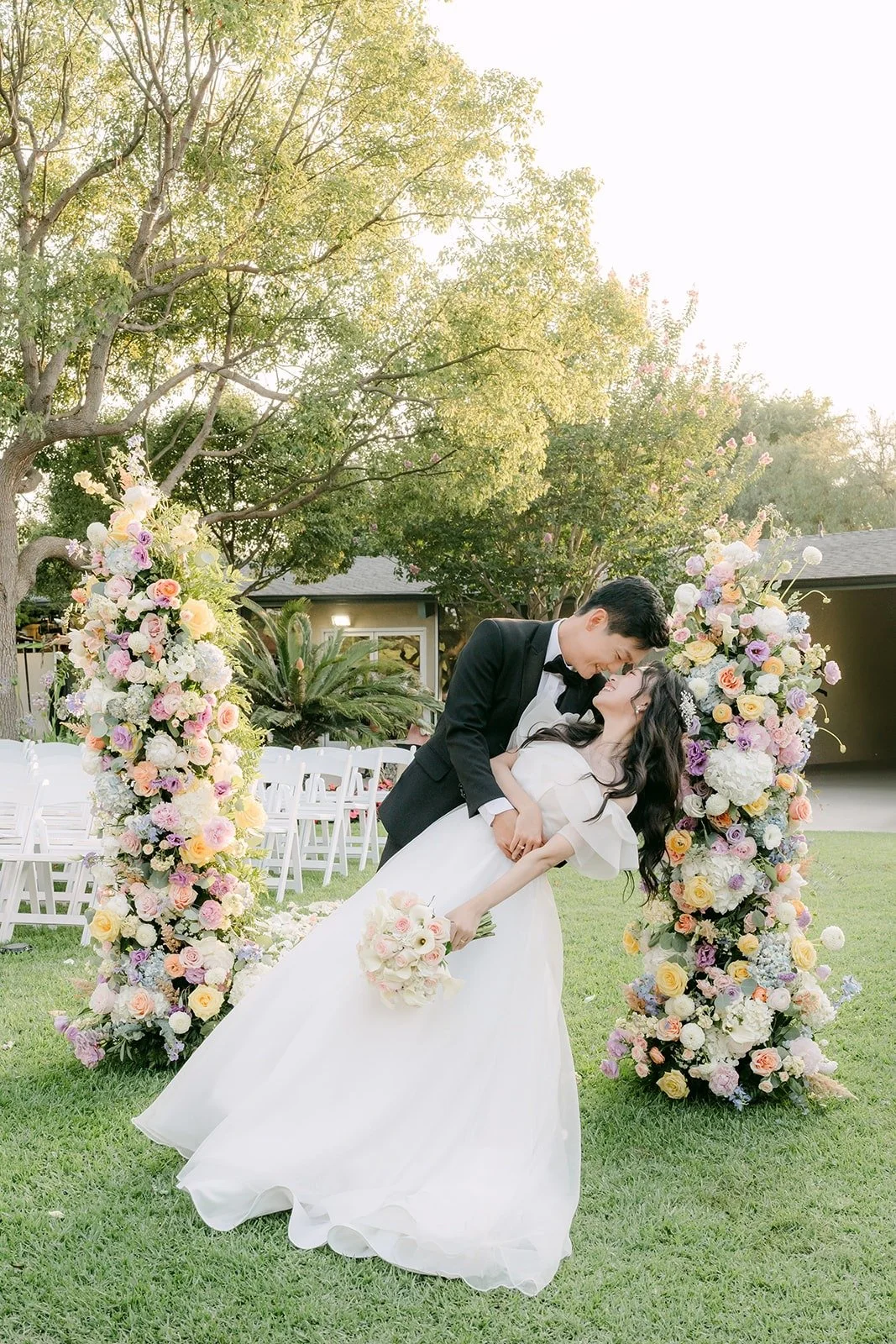 Eunsang dipping Jeannie for a kiss between the floral columns