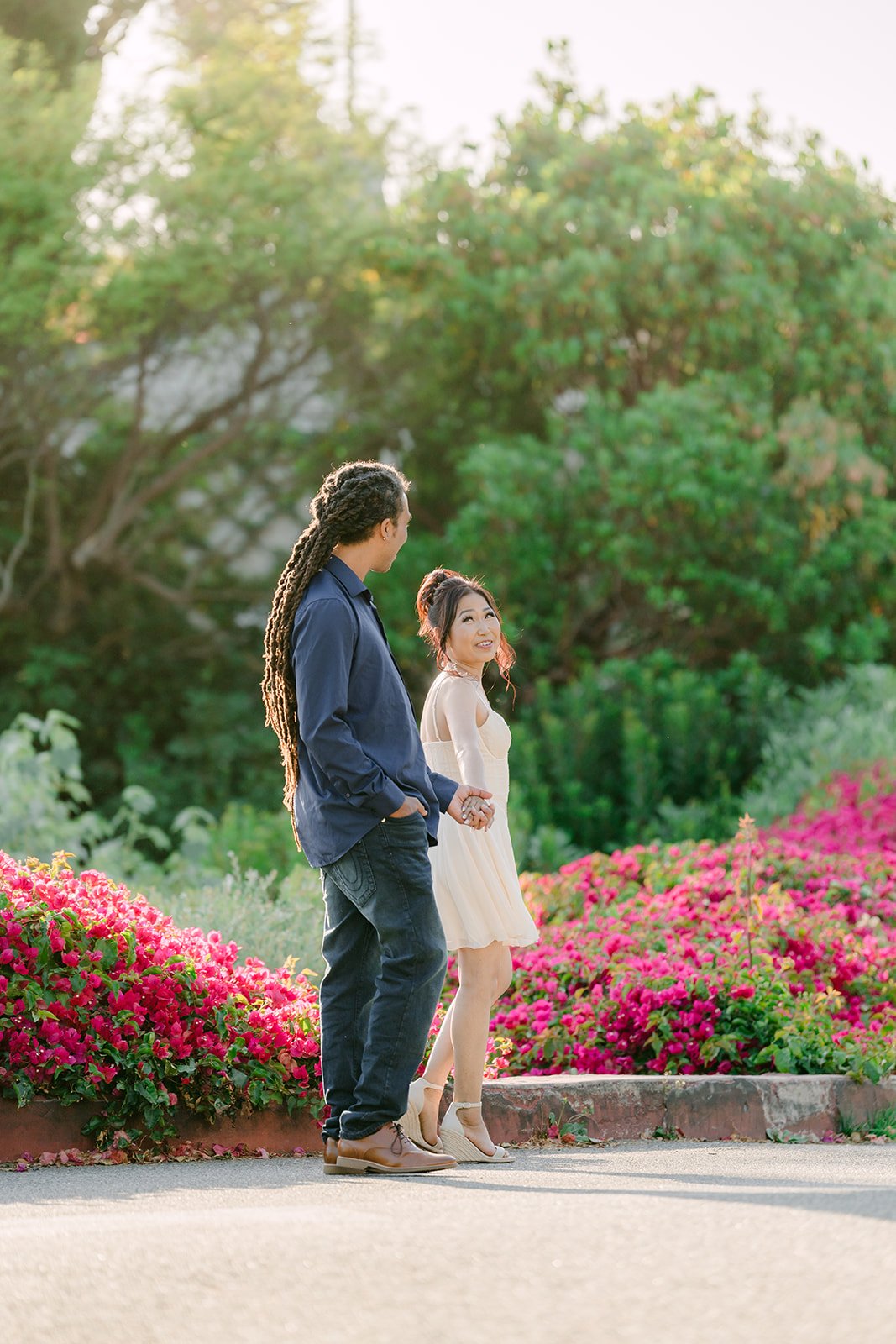 Amy and Michael standing together in front of magenta bougainvillea.