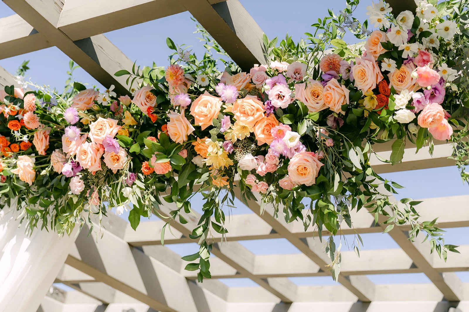 Peach and pink ceremony florals draped over the pergola at South Coast Botanic Garden