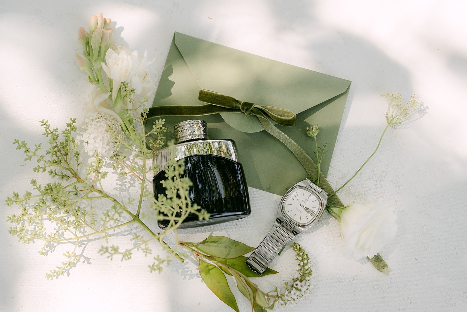 Wedding details with perfume and ring box on sage paper