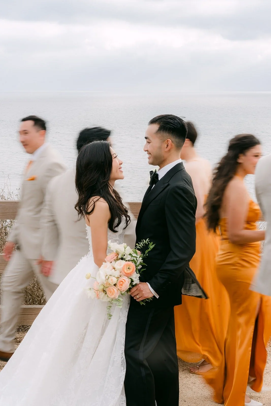 Kim and Vincent with the wedding party by the ocean fence