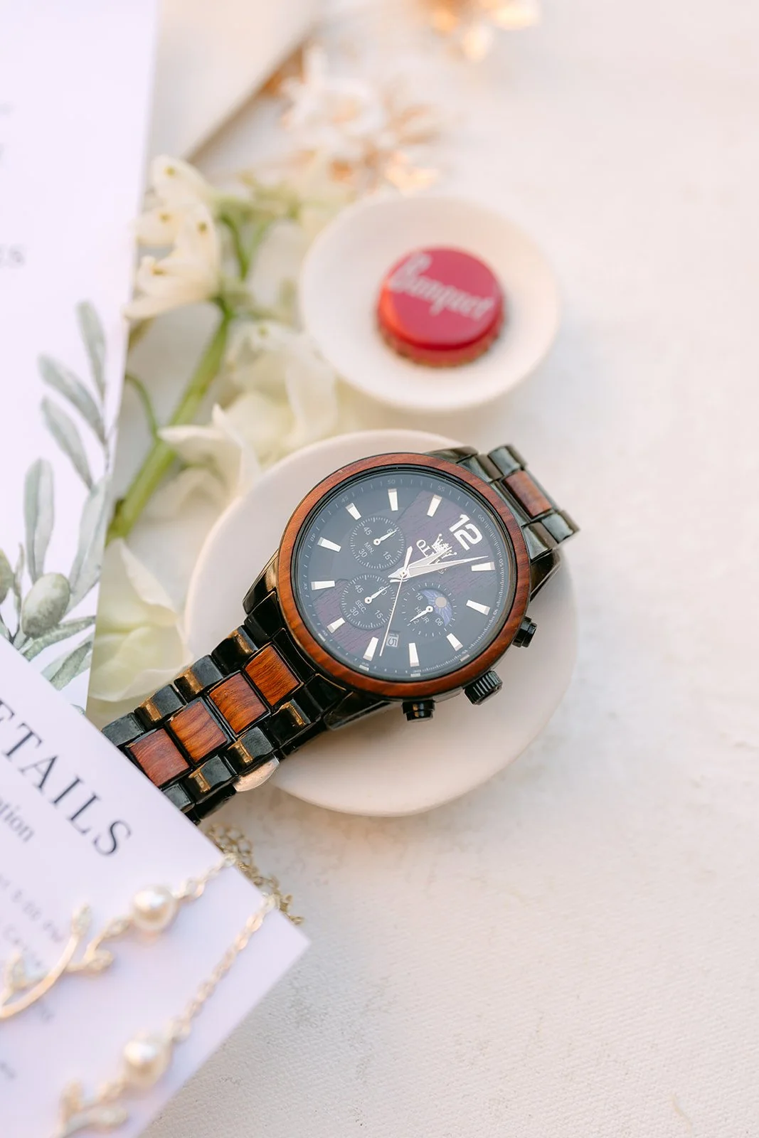 A wooden watch and wax seal styled with sage ribbon.