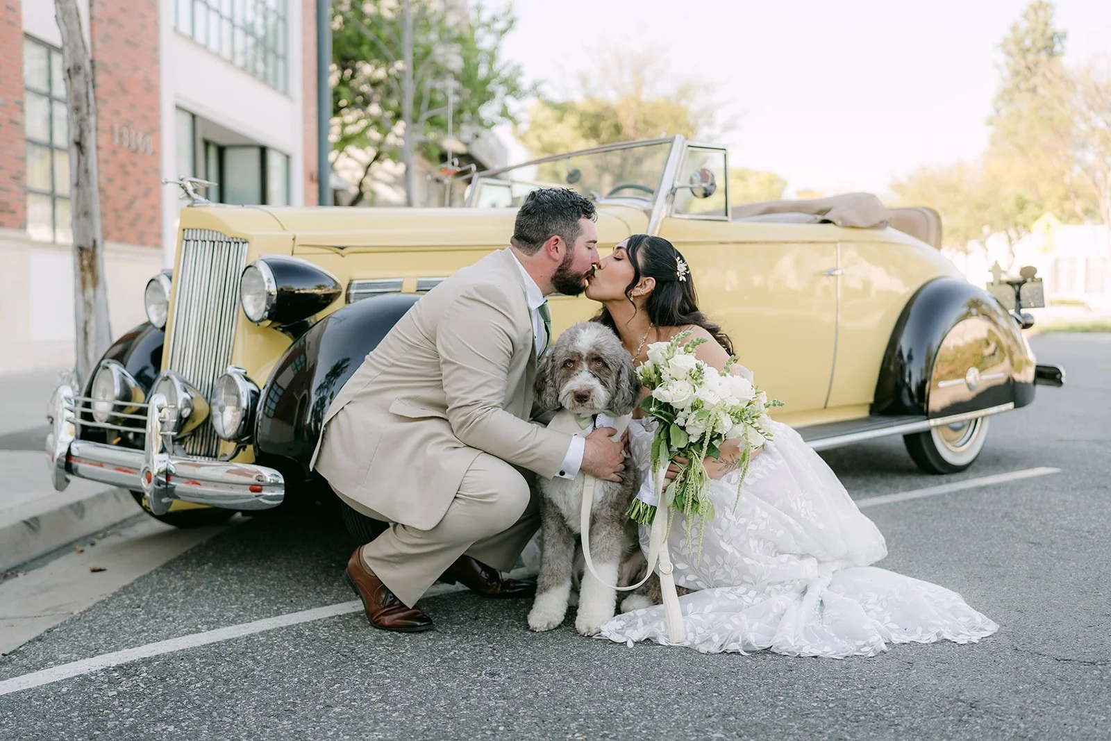 Fernanda and Cody kissing beside a yellow vintage car.