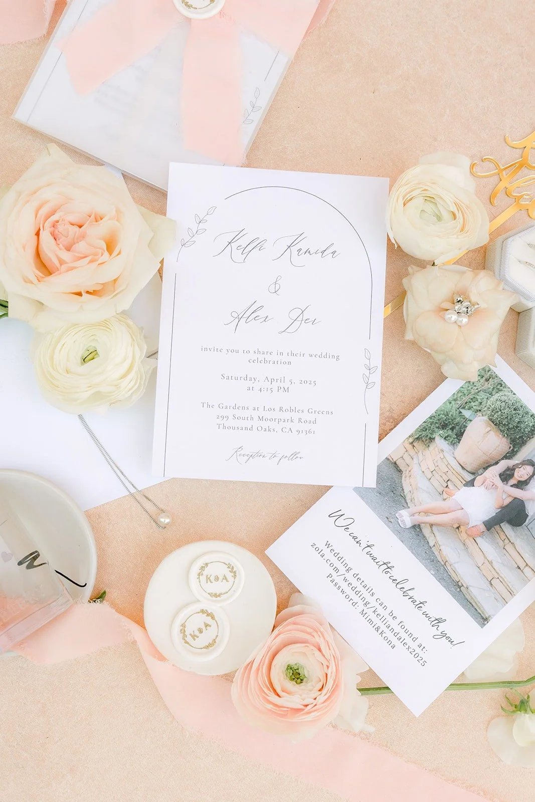 Kelli and Alex's invitation suite with an engagement photo, ring boxes and blush roses on a peach flat lay