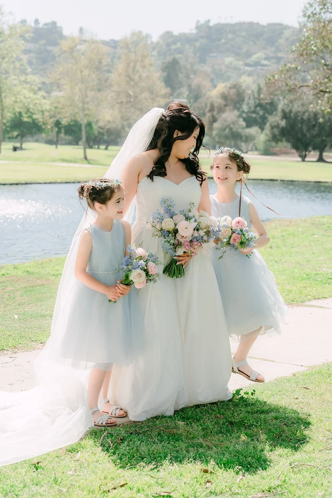 Florence walking with her bridesmaids and a flower girl by the pond
