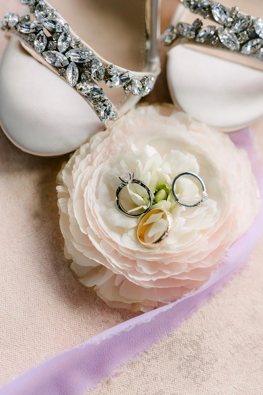 Wedding rings nestled in a ranunculus beside Vannie's heels.