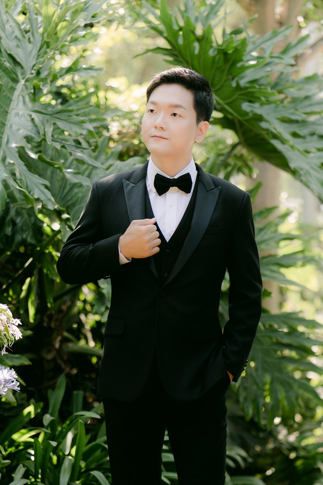 Eunsang fixing his cuff in a black tuxedo and bow tie