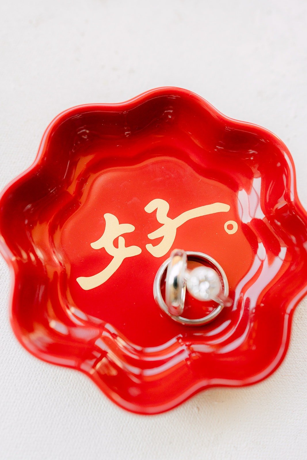 Wedding bands in a red scalloped dish with a gold character