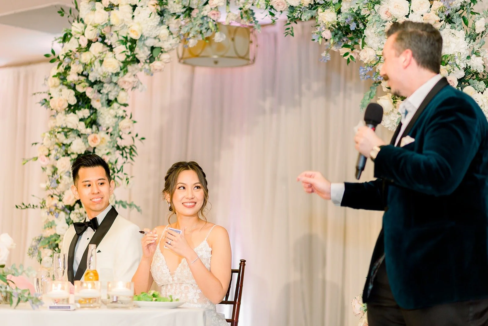 A performer on the mic beside Josephine and David's sweetheart table