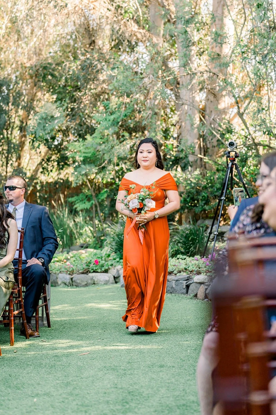 A bridesmaid in burnt orange walking down the aisle