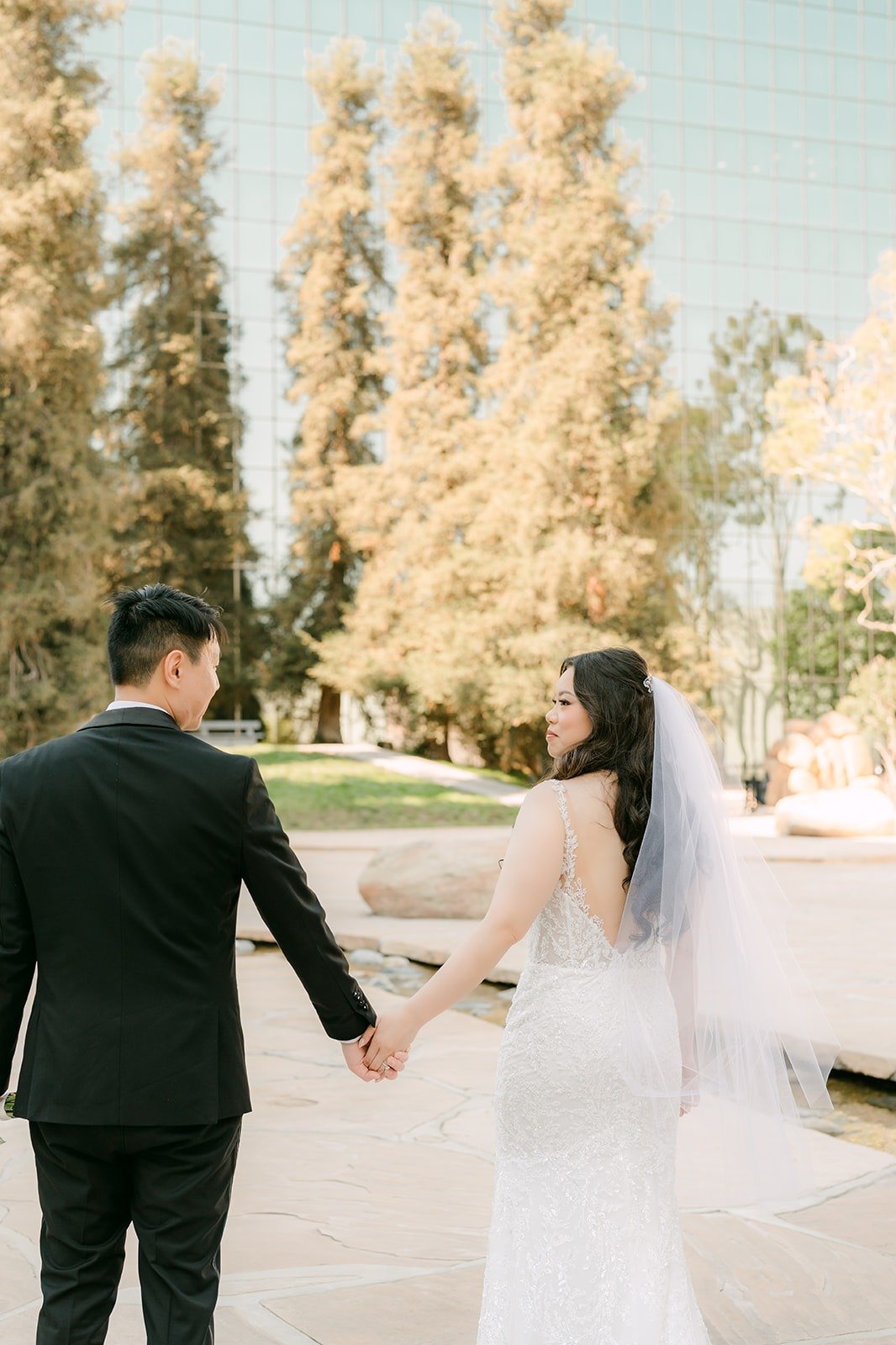Emily and James walking hand in hand by the cypress trees
