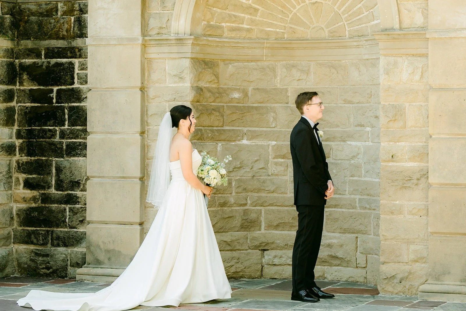 Brianna walking up to Nik under the stone archway at Greystone Mansion