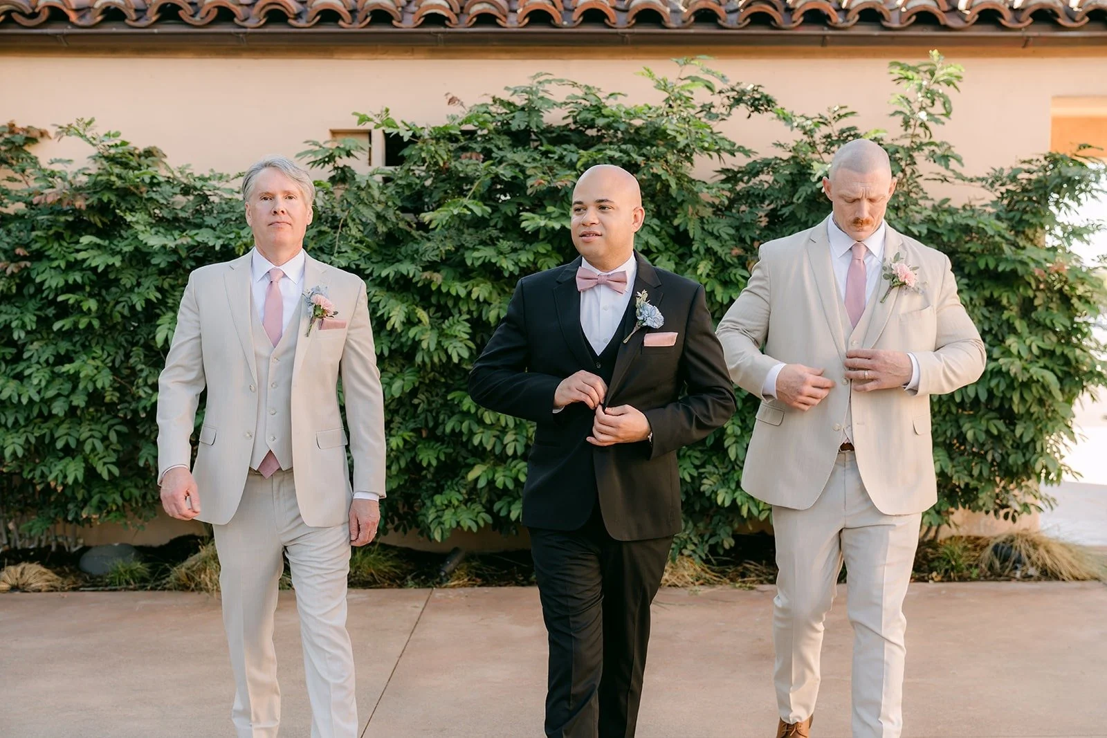 Brandon and his groomsmen in light suits in front of a green hedge, photographed by One and Only Production