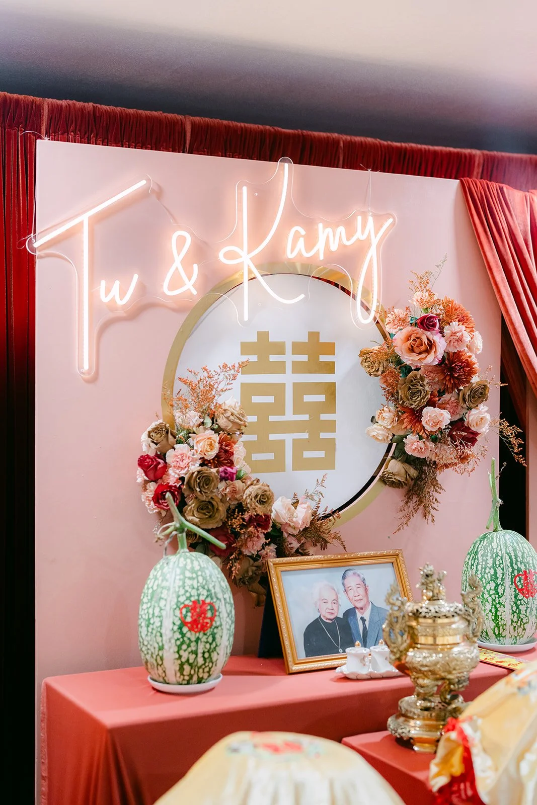 A neon sign, double happiness backdrop and florals set up for a tea ceremony at home.