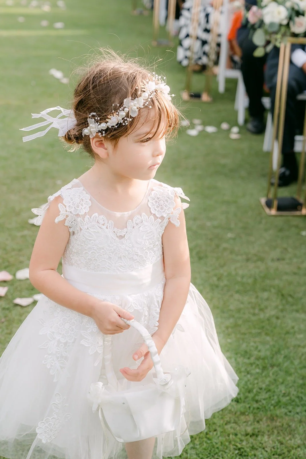 The flower girl walking down the grass aisle