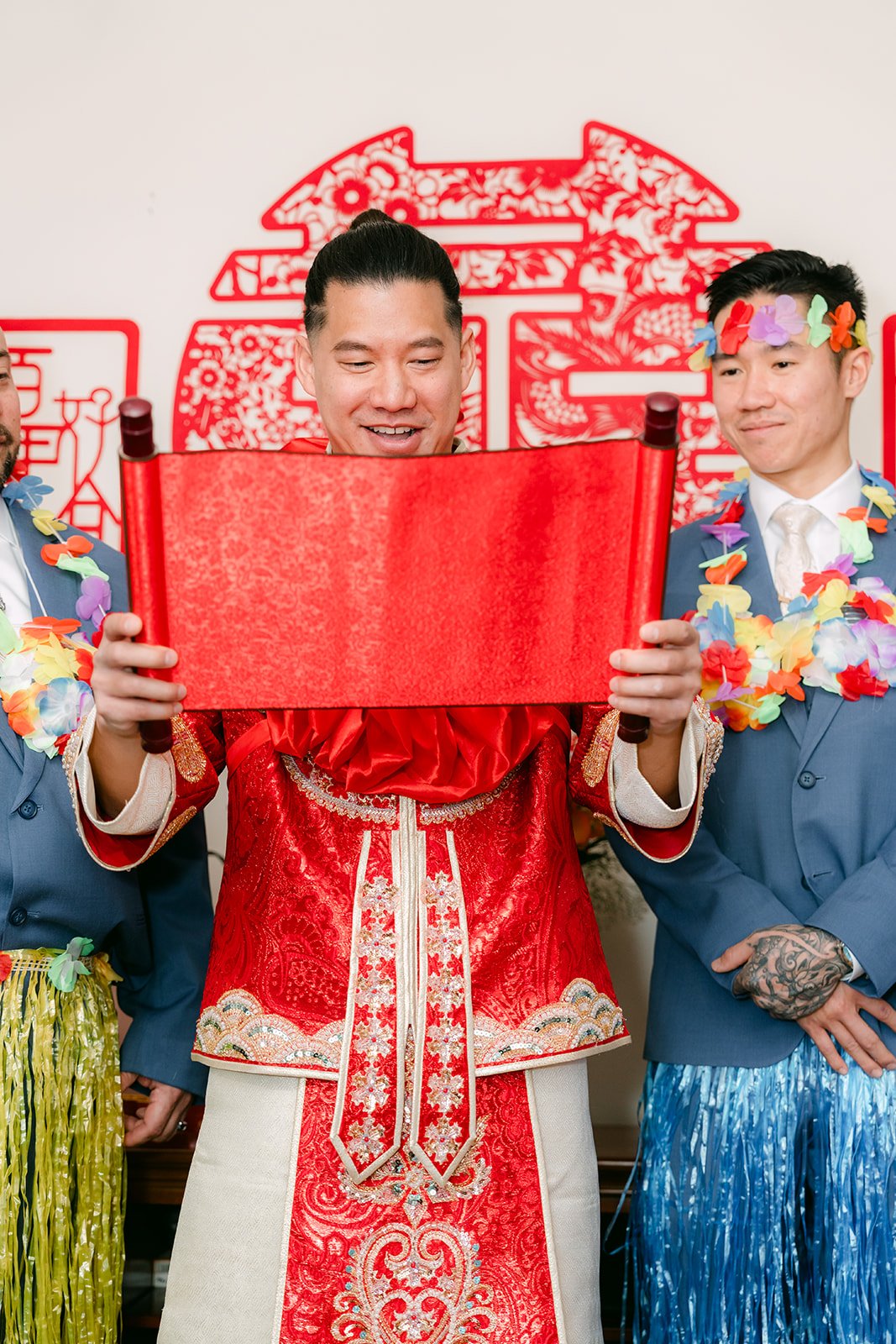 A groom holding up a red card at the door with his groomsmen beside him.