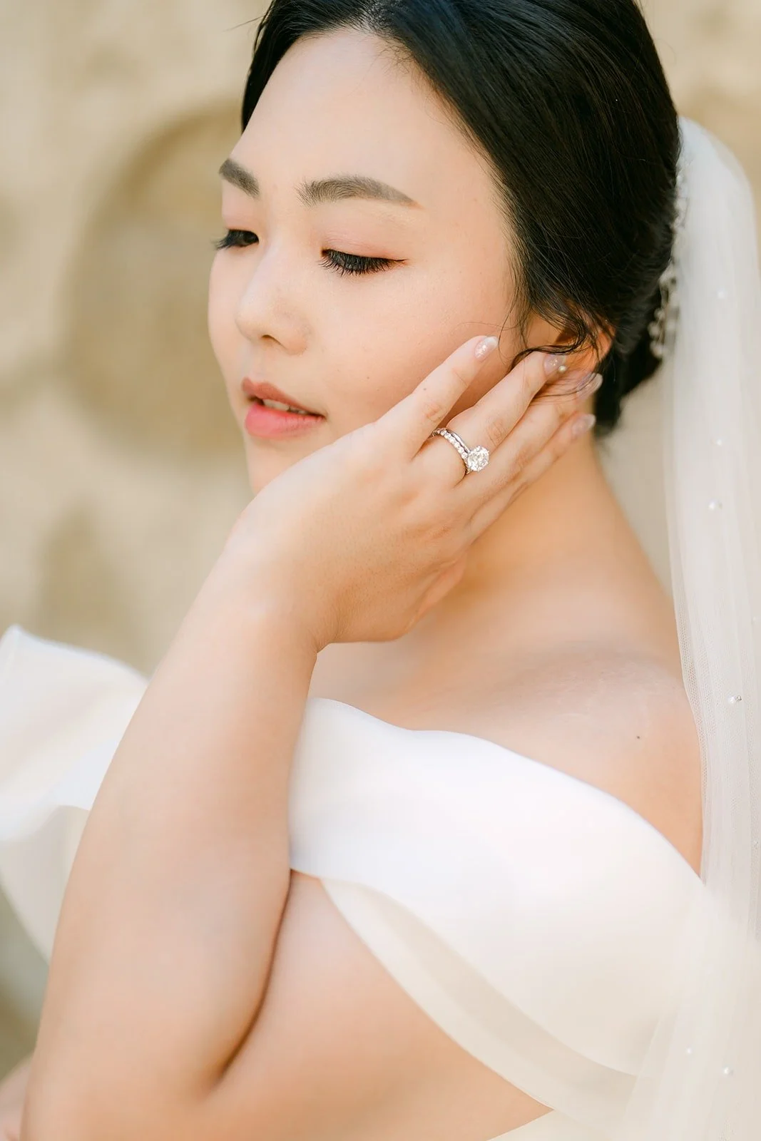 A close portrait of Chorok touching her cheek, her engagement ring in view